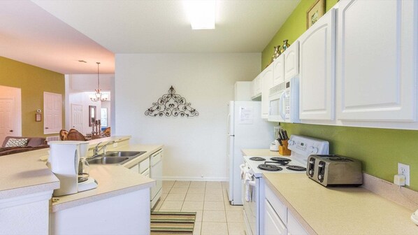 A modern kitchen with white cabinets, a built-in microwave, a stove, and a sink. - Db2633 Windsor Hills Resort Vacation Home (Kissimmee)