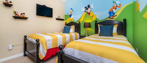 A hotel room with two beds, a television, and a mural of cartoon characters on the wall.