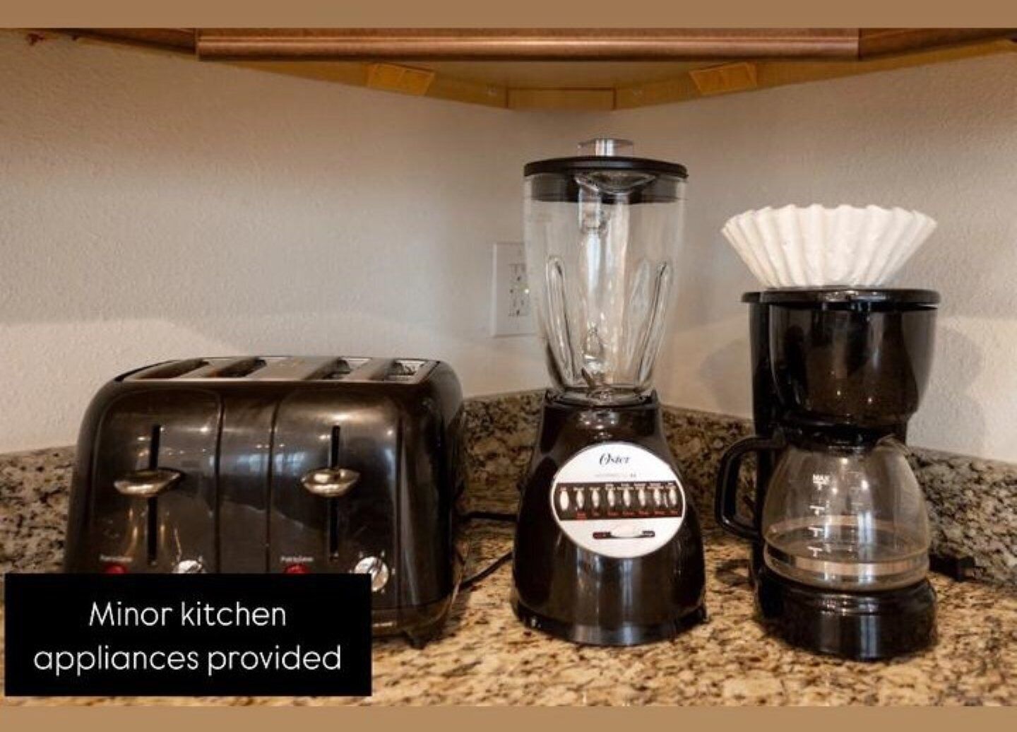 A kitchen with a blender and a coffee maker on a granite countertop.