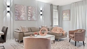 Una sala de estar moderna con sofá, sillones, una mesa de centro y obras de arte en las paredes.