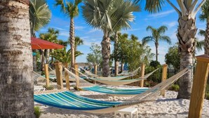 Escena de playa con hamacas y palmeras.