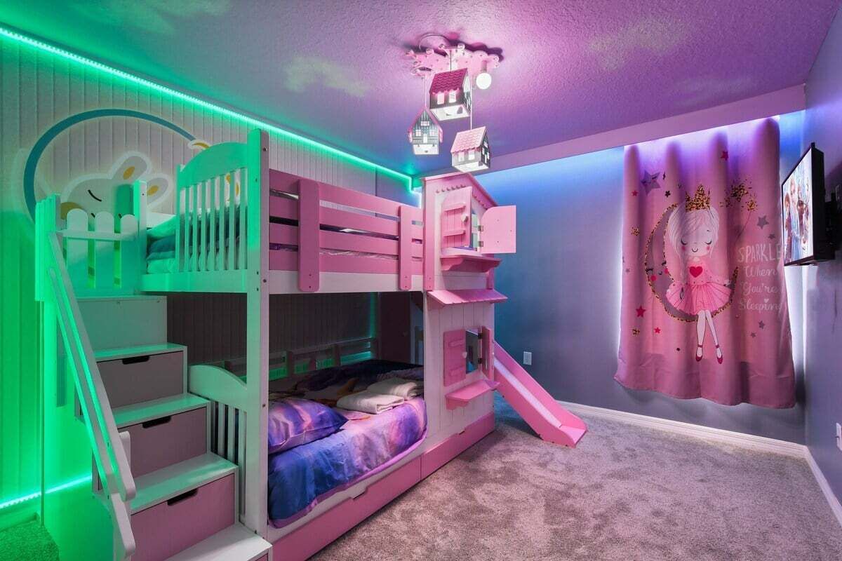 Una cama litera con tobogán, escalera y una pared con cortina.