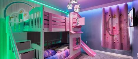 Una cama litera con tobogán, escalera y una pared con cortina.