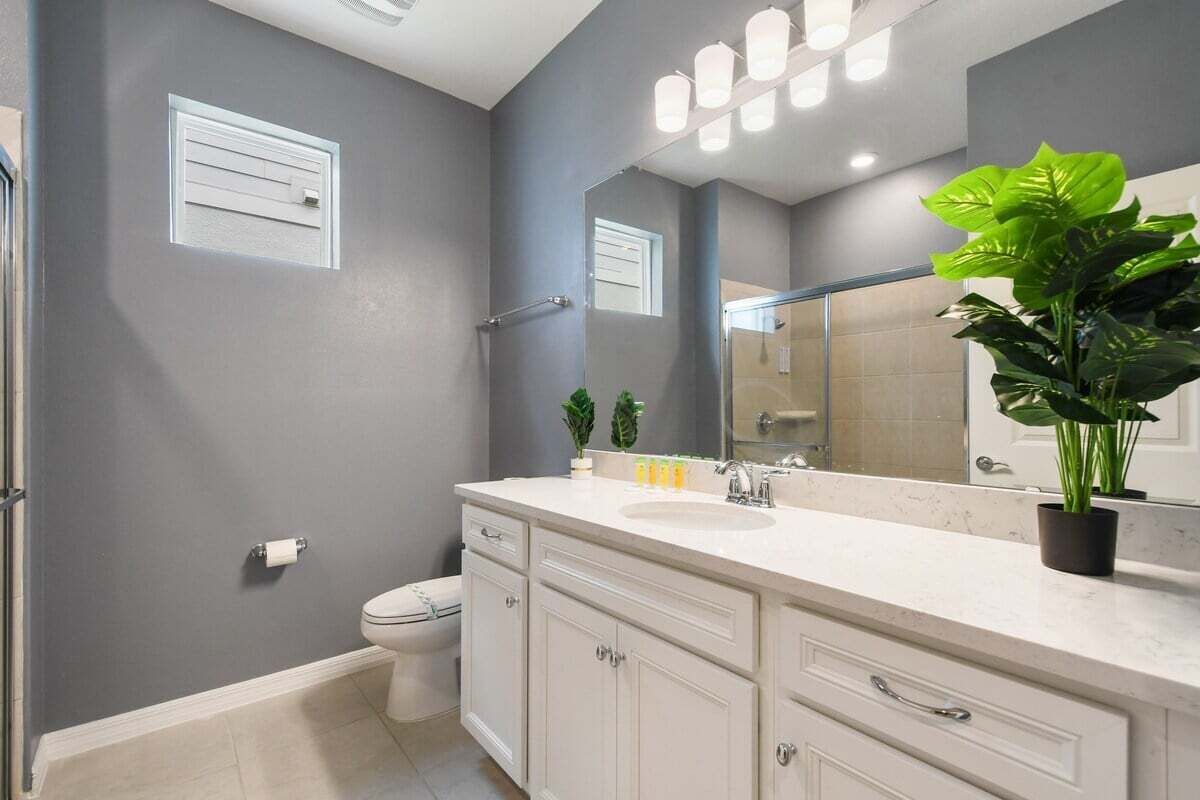 A modern bathroom with a grey wall, a white sink, and a large mirror.
