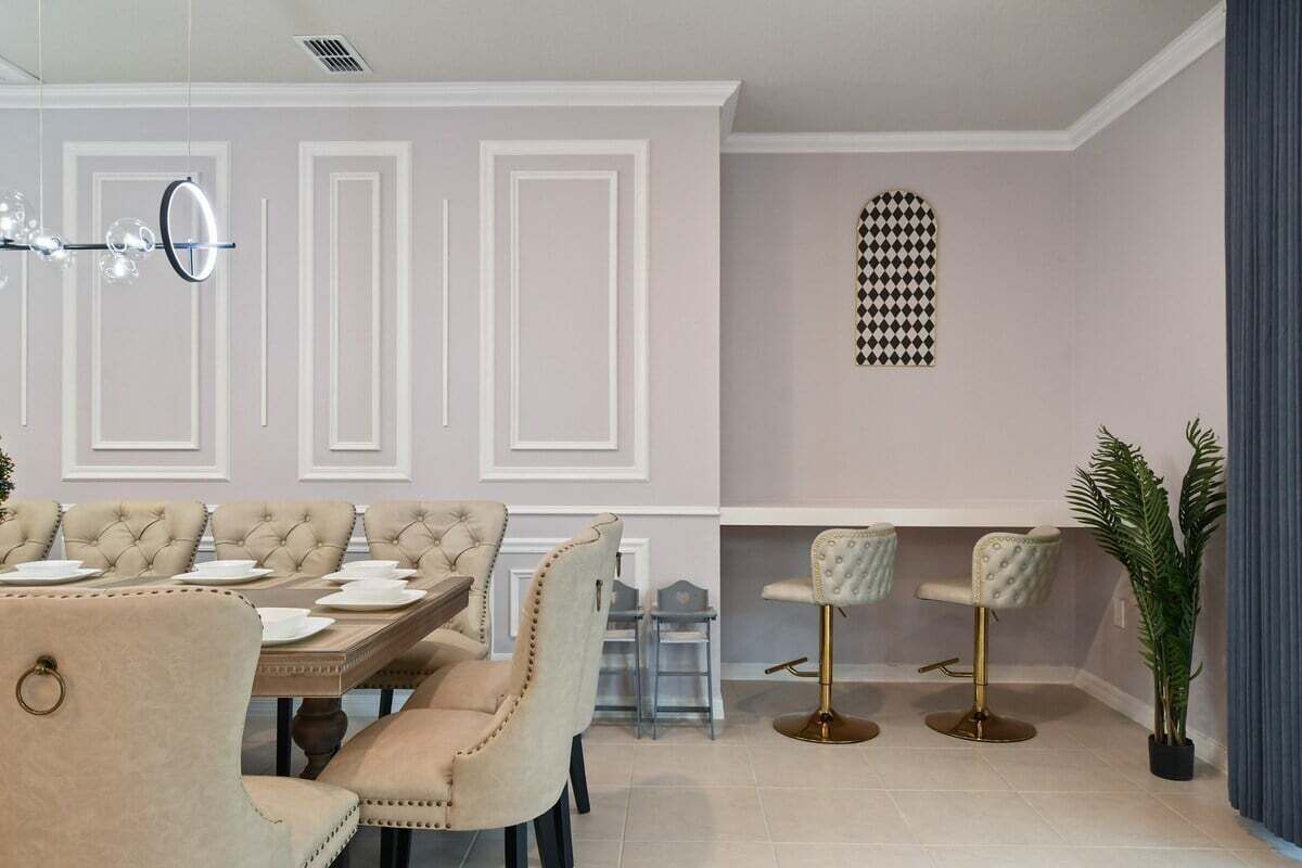 Ein Essbereich mit großem Tisch, mehreren Stühlen und einem Barhocker.