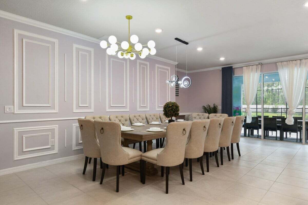 Un comedor con una mesa redonda, seis sillas, una araña y vistas amplias a través de grandes ventanales.