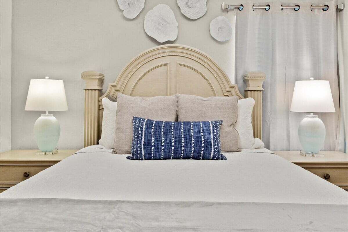 Una cama con cabecera de madera, dos lámparas de noche y decoración en la pared.