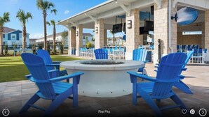 A covered outdoor seating area with blue Adirondack chairs and a central fire pit. - 3739la · Brand New 10br/pool/spa/ Disney Fireworks View (Davenport)