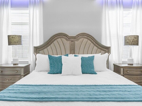 A neatly made bed with a patterned bedspread, flanked by two bedside tables with lamps, in a room with a classic headboard and curtains. - 3739la · Brand New 10br/pool/spa/ Disney Fireworks View (Davenport)