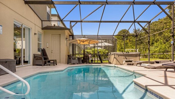 Une piscine extérieure dotée de chaises longues et de parasols, entourée d’une terrasse couverte.