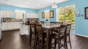 Une cuisine moderne avec des meubles blancs, un plan de travail en granit et un coin repas comprenant des chaises en bois et une table basse en verre.