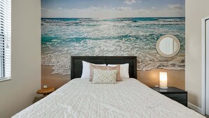 A bedroom with a bed, a nightstand, a bedside lamp, a mirror, and a view of the ocean. - 5424 Solterra Circle, Davenport,5beds (Davenport)
