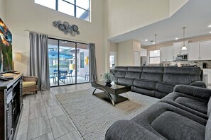Een ruime woonkamer met een grijze modulaire bank, een salontafel en een eethoek met een tafel en stoelen.