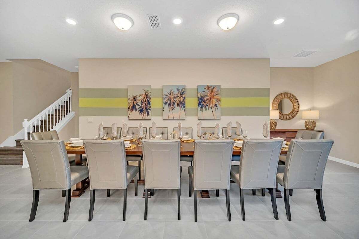 Ein Esszimmer mit einem langen Tisch, sechs Stühlen und einer Treppe im Hintergrund.