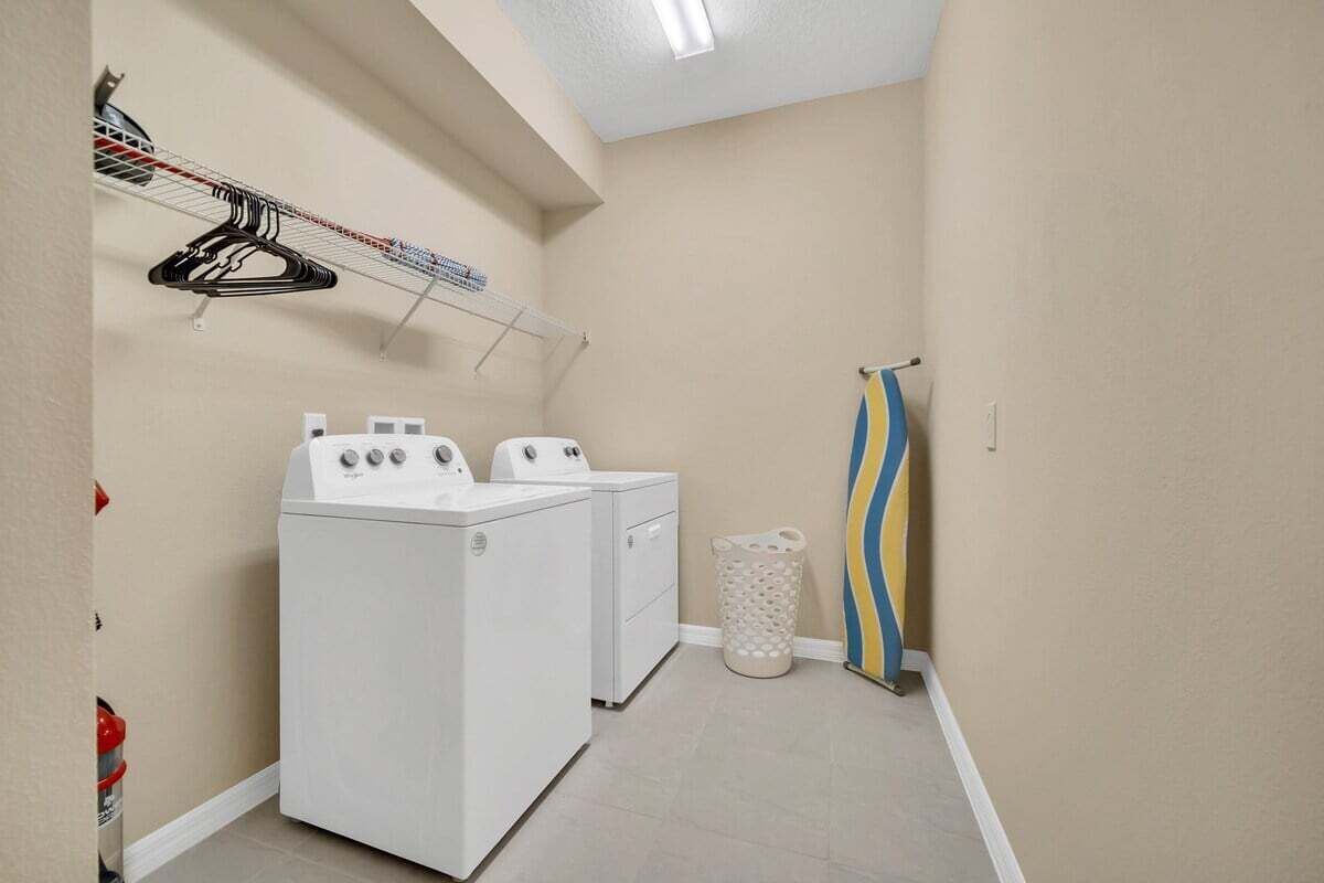 Un cuarto de lavandería con dos lavadoras, un tendedero y un basurero.