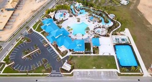 An aerial view of a resort with a large swimming pool, a tennis court, and a parking area. - 2037 Lelani Cir · Brand New 10bd Mansion At Windsor Island Resor (Davenport)