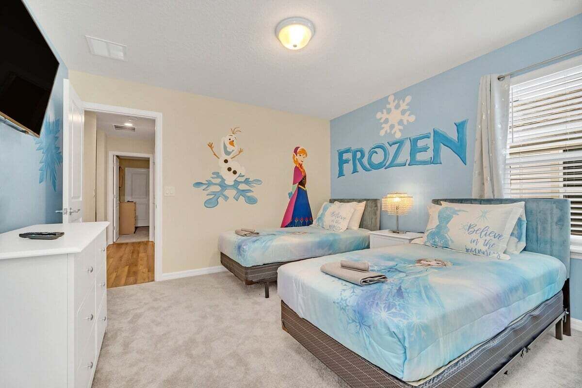 A bedroom with two beds, a dresser, a TV, and a wall mural.
