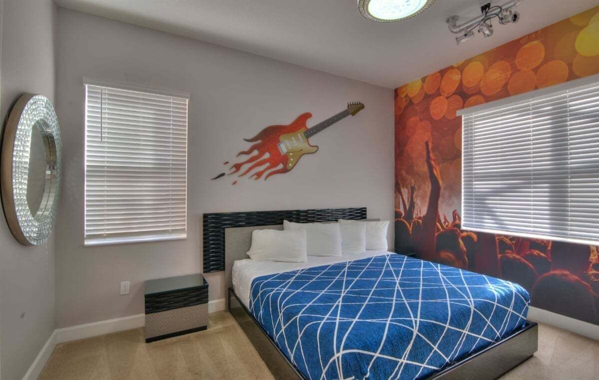Een slaapkamer met een bed, een muurschildering en een raam met jaloezieën.