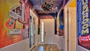 A hallway with a mural on the left wall, a door at the end, and a neon sign on the right. - 4011-ol-music Genres Themed With Bowling Alley (Davenport)