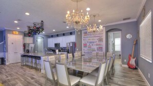 A modern kitchen with a central island, bar stools, and a chandelier. - 4011-ol-music Genres Themed With Bowling Alley (Davenport)