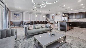 A modern living room with a grey sofa, a coffee table, and a staircase leading to an upper floor. - 3727la - Brand New 10beds Villa at Windsor Island/pool/spa/firew (Davenport)