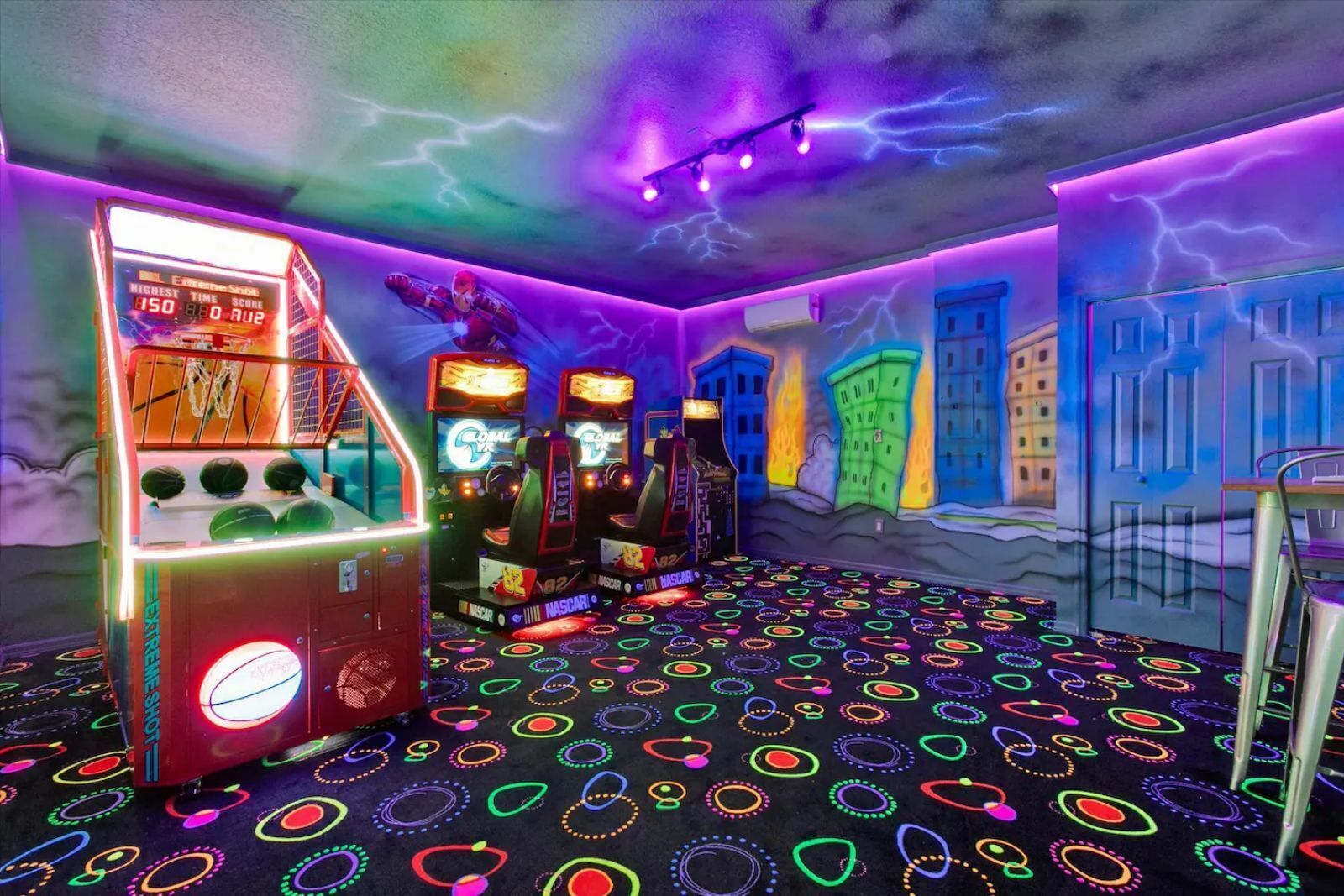 A gaming arcade with neon lights and racing game machines.