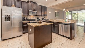 A modern kitchen with dark cabinetry, stainless steel appliances, granite countertops, and pendant lighting. - Amazing Home in Davenport 4br 3.5 Bath (Davenport)