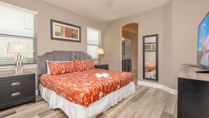 A bedroom with a large bed, a nightstand, a dresser, a lamp, and a TV. - Amazing Home in Davenport 4br 3.5 Bath (Davenport)