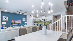 A modern living room with a white sofa set, a dining table with a vase, and a kitchen in the background. - Psd816 (Davenport)