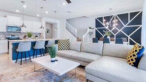 Ein modernes Wohnzimmer mit einer Couch, einem Couchtisch und einer Küchenzeile mit Bar.