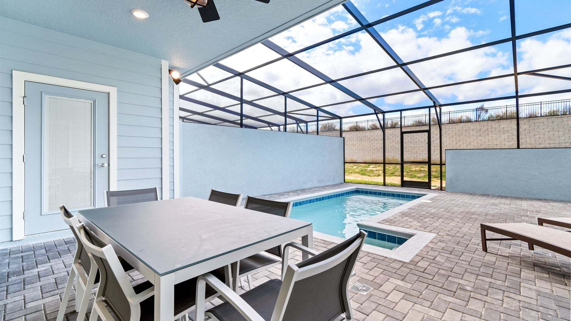 Un patio al aire libre con piscina, una mesa y sillas.