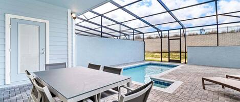 Un patio al aire libre con piscina, una mesa y sillas.
