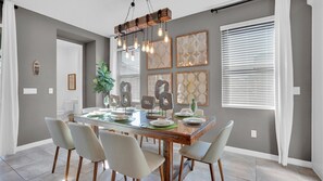 Un comedor con una mesa de madera, seis sillas y una lámpara colgante.