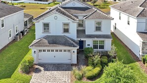 A two-story house with a tiled roof, a garage, and a well-maintained lawn. - 1674 Moon Valley DR, Davenport, 6bed (Davenport)