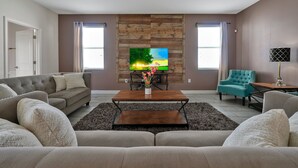 A living room with a sofa, a coffee table, a TV, and a chair. - 1674 Moon Valley DR, Davenport, 6bed (Davenport)