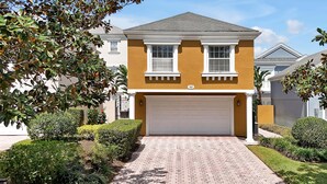 A two-story house with a garage, surrounded by well-maintained hedges and a brick driveway. - 7407 Excitement Drive, Kissimmee, Unit A, 1 BED (Kissimmee)