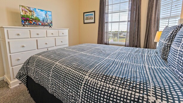 A bedroom with a bed, a dresser, a painting, and a window with curtains. - Windsor Hills Resort 3 Bedroom 4th Floor Condo With Resort Access 0946 (Kissimmee)