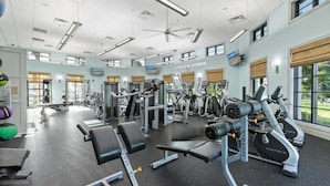 A gym with various exercise machines, a bench press, and a television screen. - Myr1466 (Davenport)