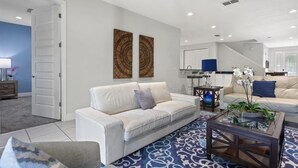A modern living room with a white sofa, a coffee table, and two decorative wall pieces. - 360-7-pc-large and Luxury Villa (Kissimmee)