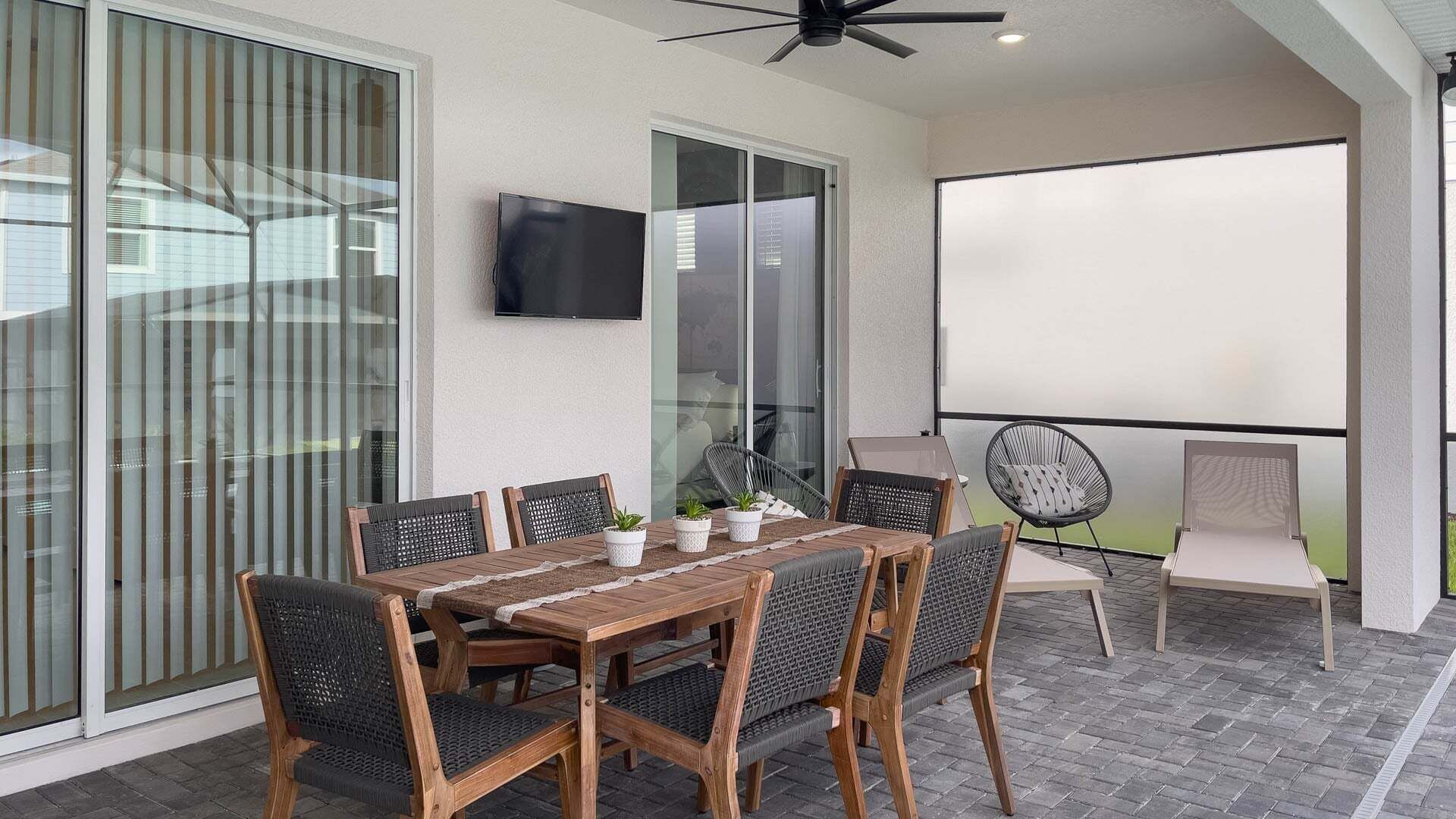 A patio with a table and chairs, a ceiling fan, and a TV mounted on the wall.