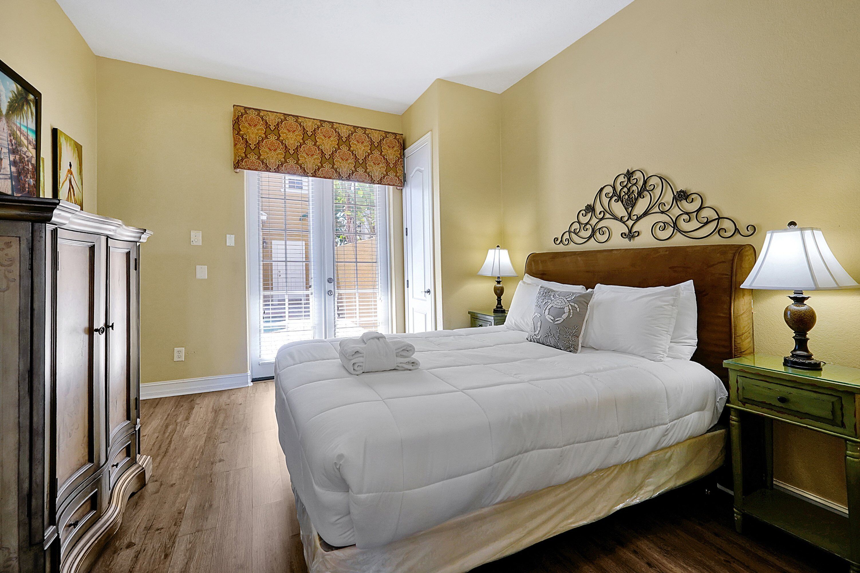 A neatly made bed with white bedding, a wooden headboard, and two bedside lamps.