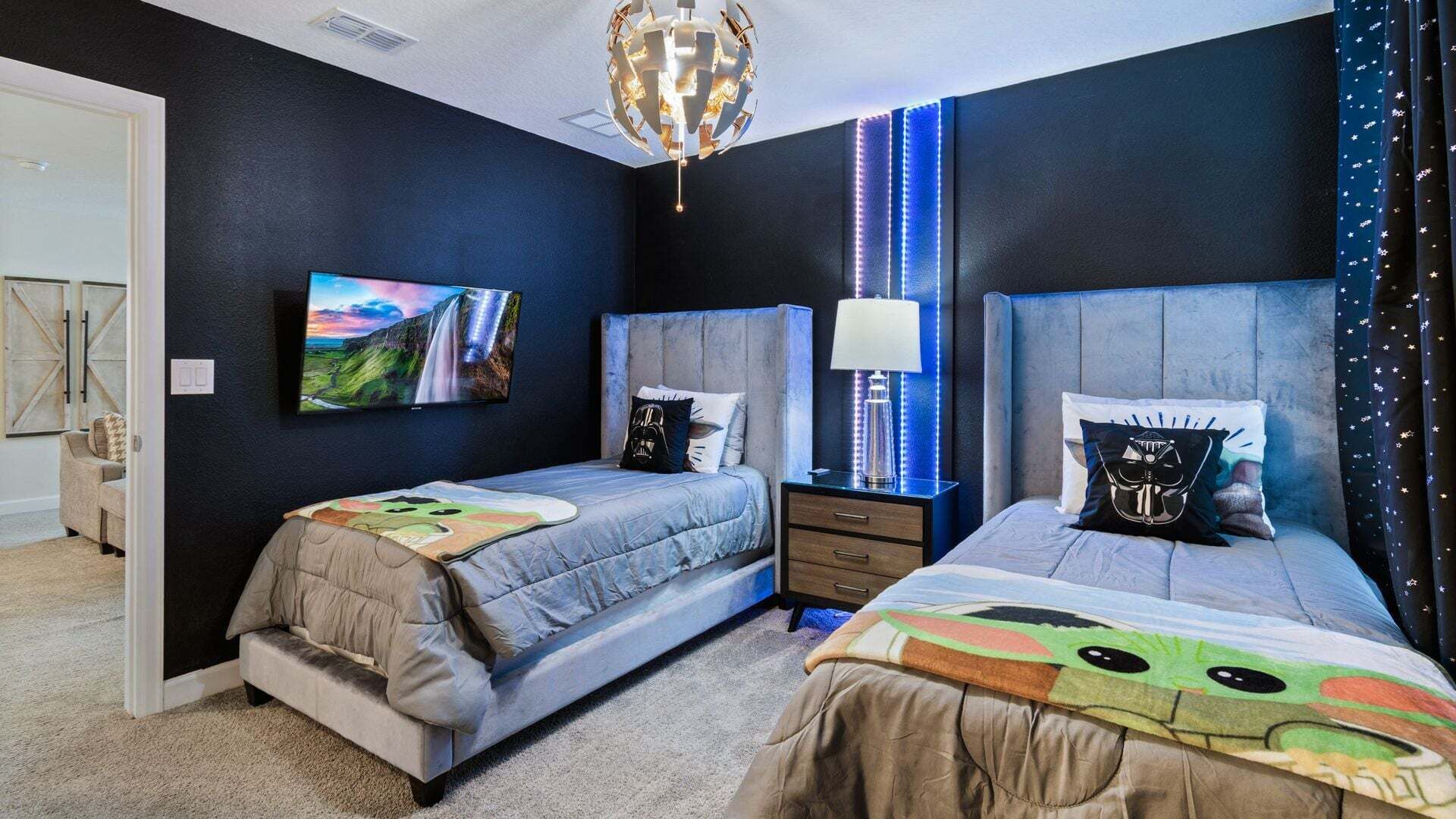 Un dormitorio con dos camas, televisión, lámpara y una original lámpara de techo.
