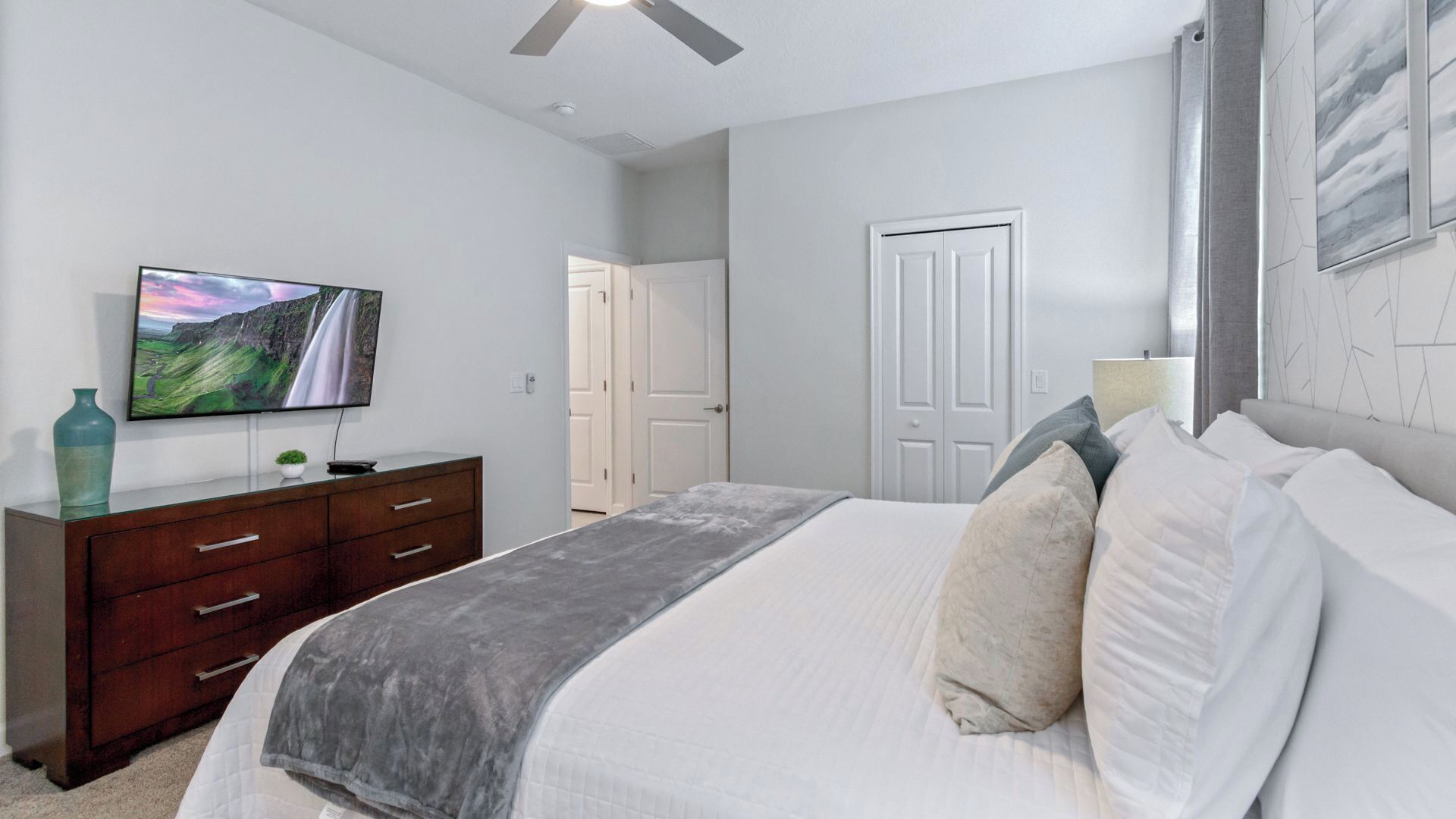 Un dormitorio con una cama, un aparador, un televisor y una puerta.