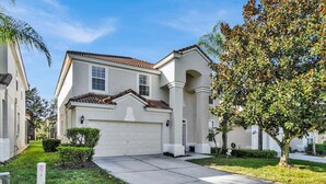 A residential house with a garage, a driveway, and a well-maintained lawn. - Grs7756 (Kissimmee)
