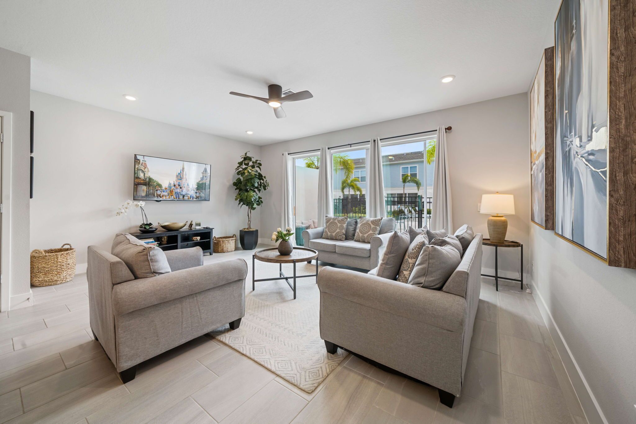A modern living room with two sofas, a coffee table, a TV, and a ceiling fan.
