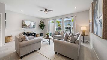 A modern living room with two sofas, a coffee table, a TV, and a ceiling fan.