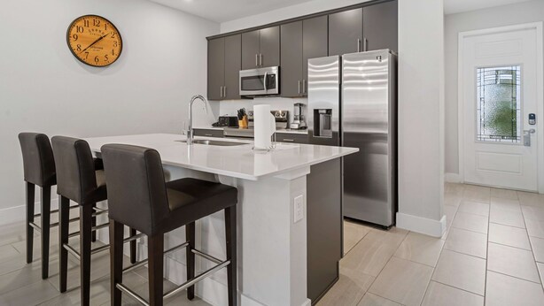 A modern kitchen with a central island, stainless steel appliances, and a clock on the wall. - Kd912s Eagle Trace Marine (Kissimmee)