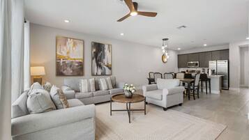 A modern living room with a sofa, armchair, coffee table, and artwork on the wall.