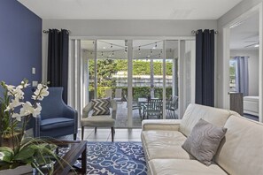A modern living room with a sofa, armchair, and a coffee table. There is a view of a patio area with outdoor furniture. - 350-360 Huge Villas - Near Disney - 15 BDs (Kissimmee)