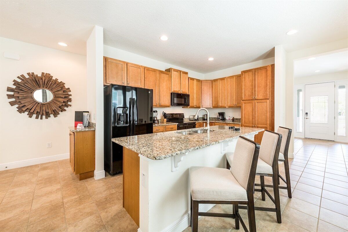 Una cocina moderna con armarios de madera, encimera de granito y una isla integrada con taburetes de bar.